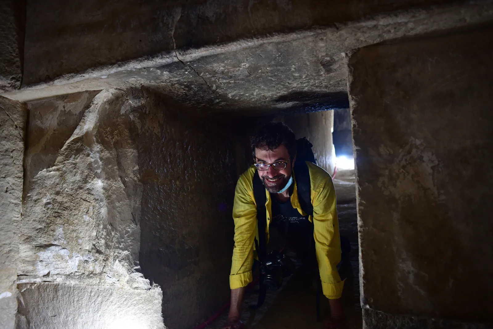 På huk genom en av Knäckta pyramidens trånga gångar, troligen den grovhuggna förbindelsetunneln (omkring 0,74 × 0,92 meter) mellan det nedre och det övre kammarsystemet.