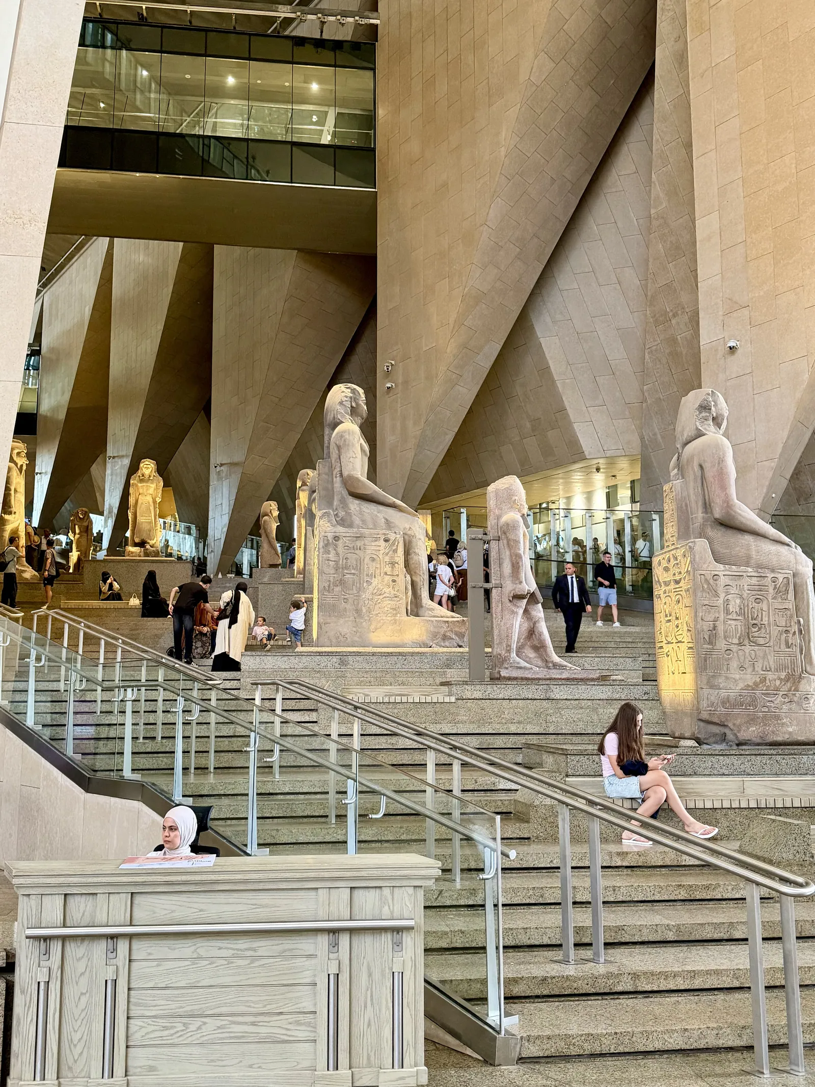 Den stora trappan (foto aug. 2026): sex våningar kantade av ett sextiotal monumentala statyer, sarkofager och byggnadsdelar, med ett fönster mot Gizapyramiderna högst upp.