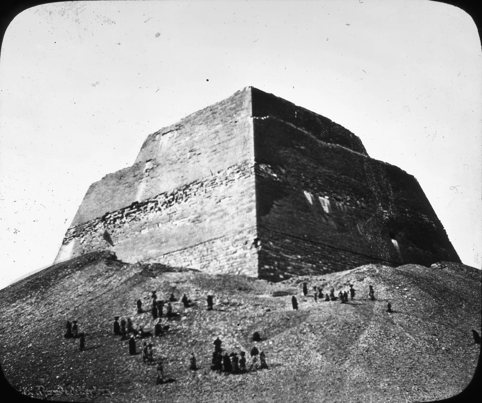 Skioptikonbild från Brooklyn Museum (före 1923): Meidumpyramidens trappstegade torn som reser sig ur kjolen av rasmassor, med människor vid foten som skala.