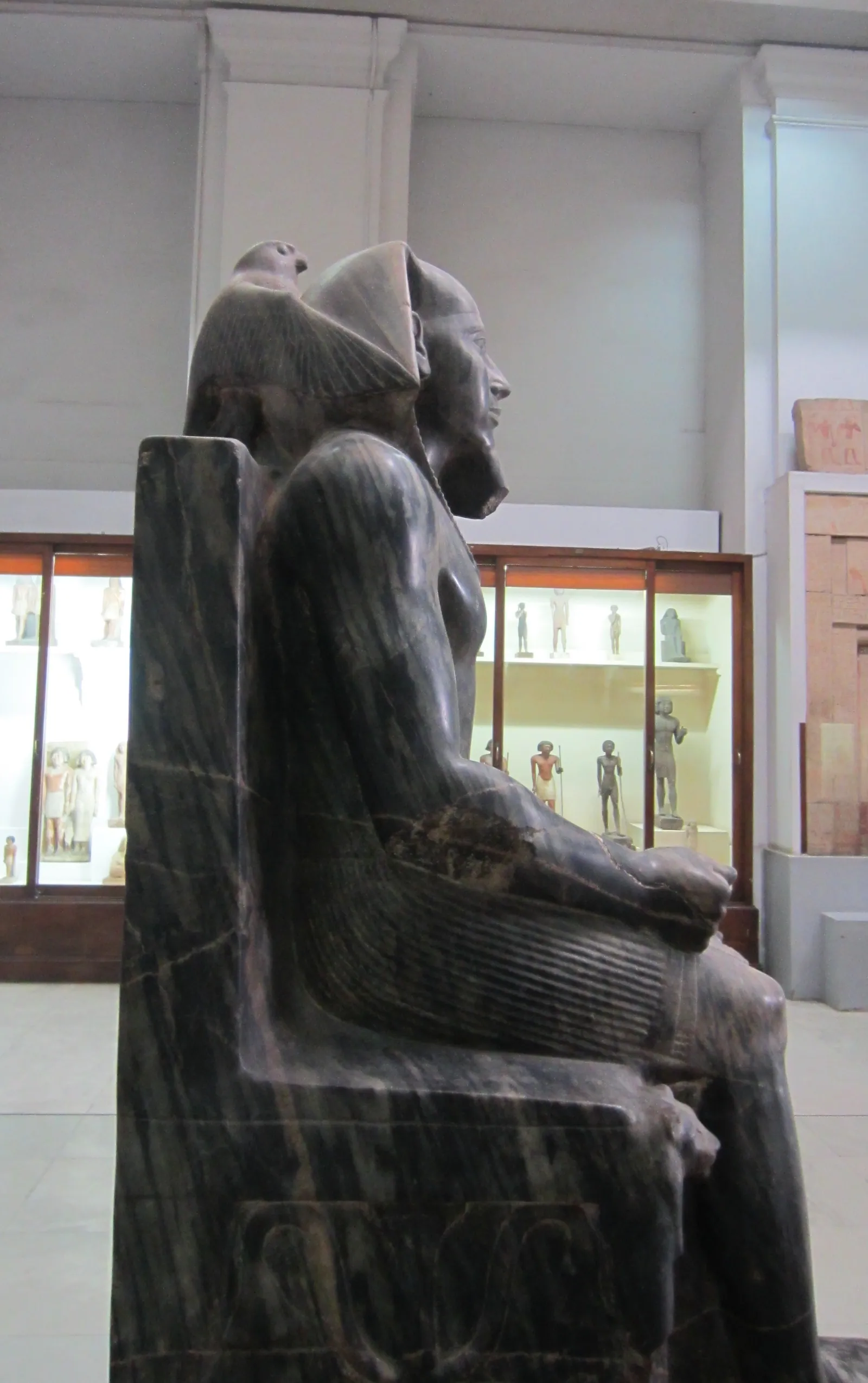 Chefren på tronen (från hans dalens tempel i Giza; Egyptiska museet i Kairo). Falken Horus breder ut vingarna bakom kungens huvud – kungen som den levande Horus, synliggjord.