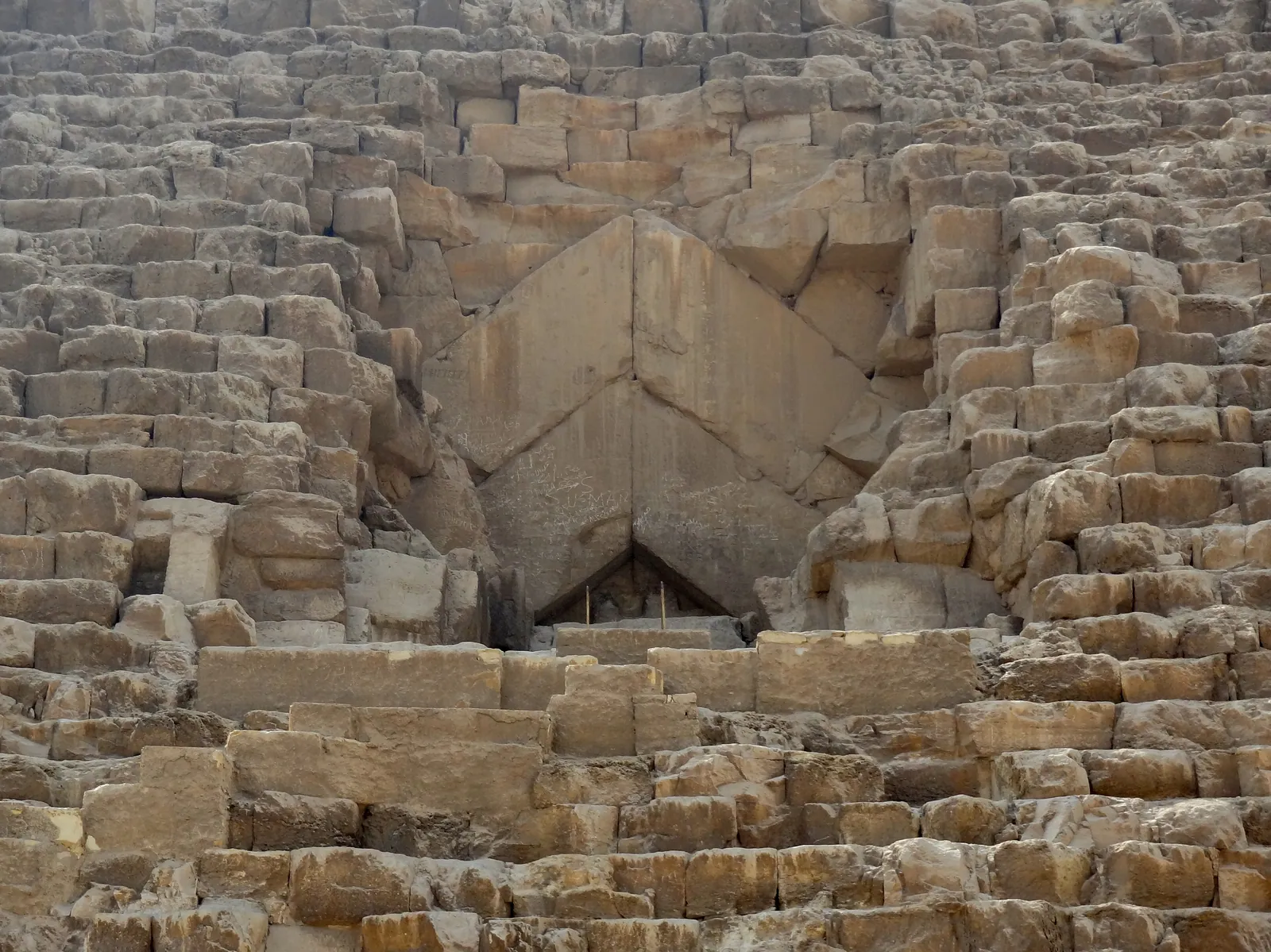 Den stora pyramidens ursprungliga ingång med sina två par väldiga gavelblock av kalksten. Bakom dem ligger North Face Corridor, en gång på ungefär 9 meter med cirka 2 × 2 meters tvärsnitt. ScanPyramids hittade den med myonmätningar, och den filmades för första gången med endoskop i februari–mars 2023.