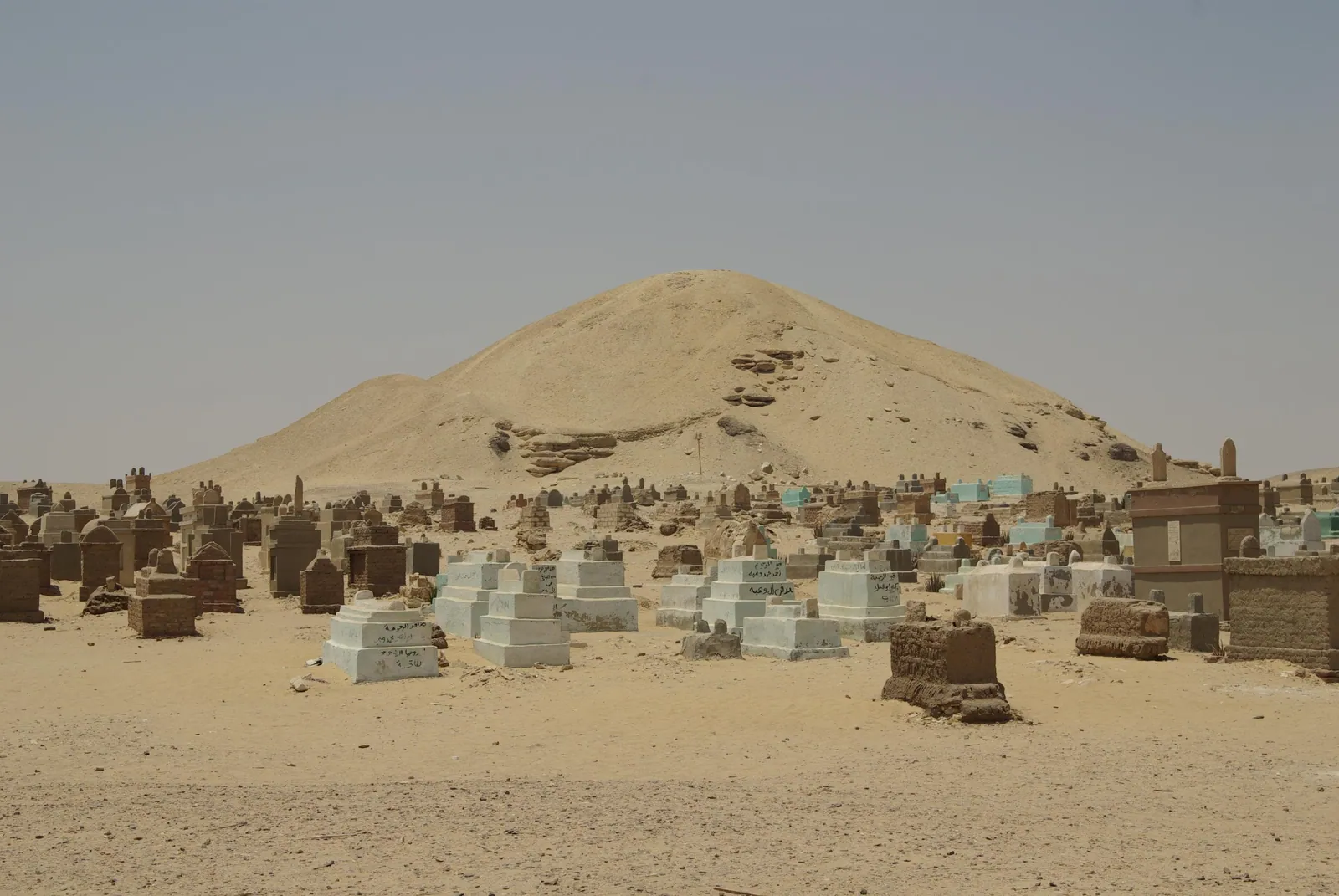 Grushögen som är Amenemhet I:s pyramid i norra Lisht (ca 1985–1956 f.Kr.), i dag ungefär 20 m hög, bakom byns muslimska begravningsplats som fortfarande används – visa hänsyn. Kärnan är full av reliefblock tagna från Gamla rikets monument åt Cheops, Chefren, Unas och andra.