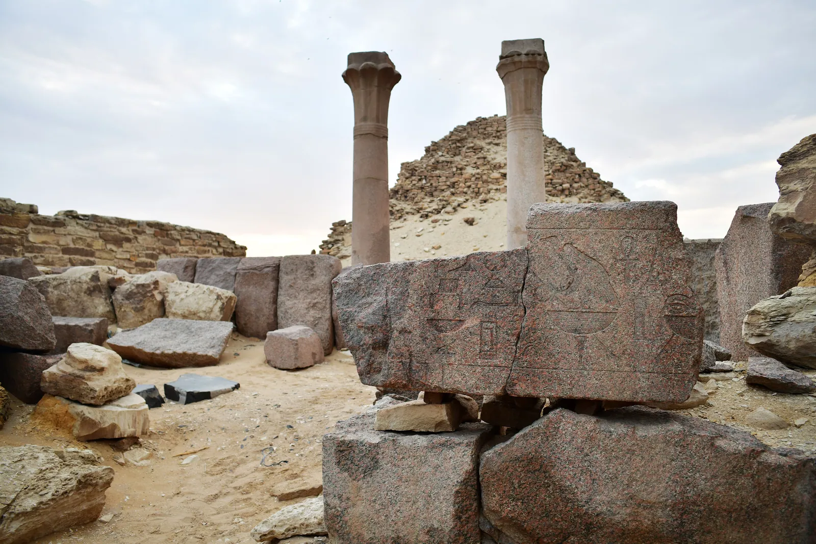 Hieroglyfer huggna i röd granit vid Sahures anläggning – en del av kungens titulatur som en gång löpte längs arkitravar och dörrinramningar.