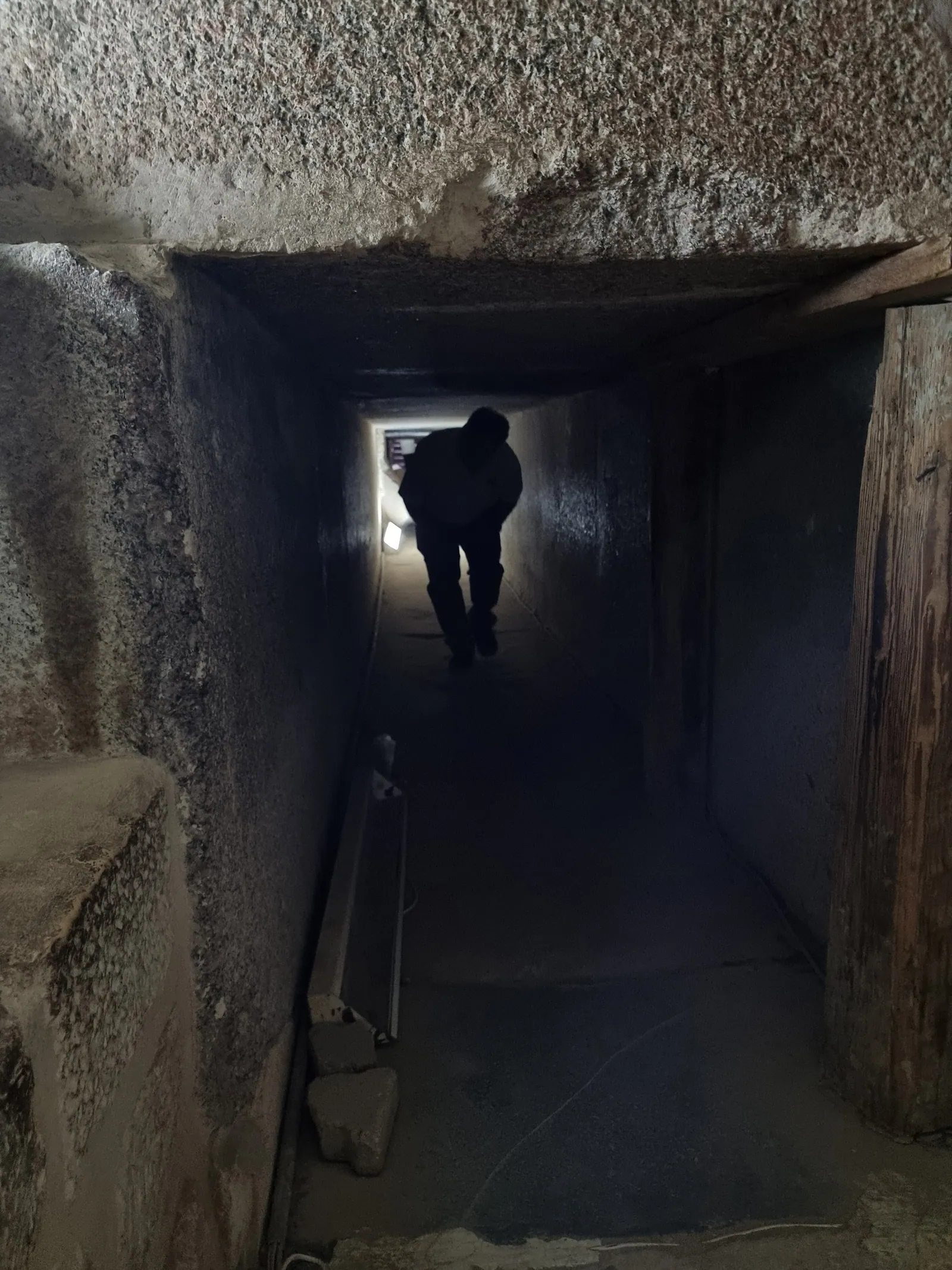 Dubbelvikt i den granitklädda gången i Tetis pyramid (2022). Gången leder förbi platsen för de tre sönderslagna fällstenarna in till de inskriftsprydda kamrarna.